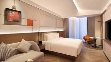 Una habitación de hotel con una cama, un sofá, una mesita y un televisor.