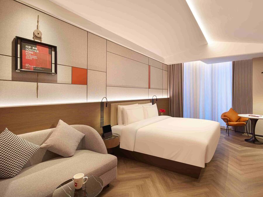 Una habitación de hotel con una cama, un sofá, una mesita y un televisor.