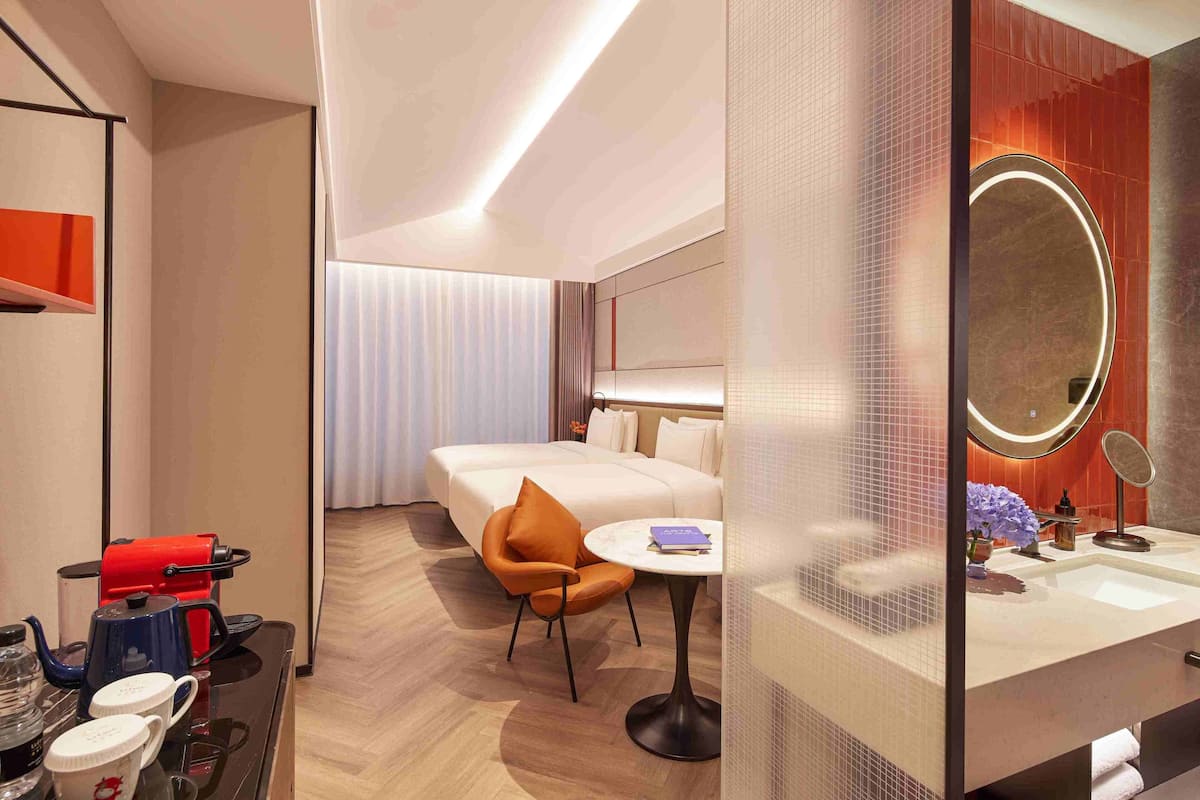 Une chambre d’hôtel comprenant un lit, un coin salon avec une table, une machine à café et une salle de bain avec un miroir et un lavabo.