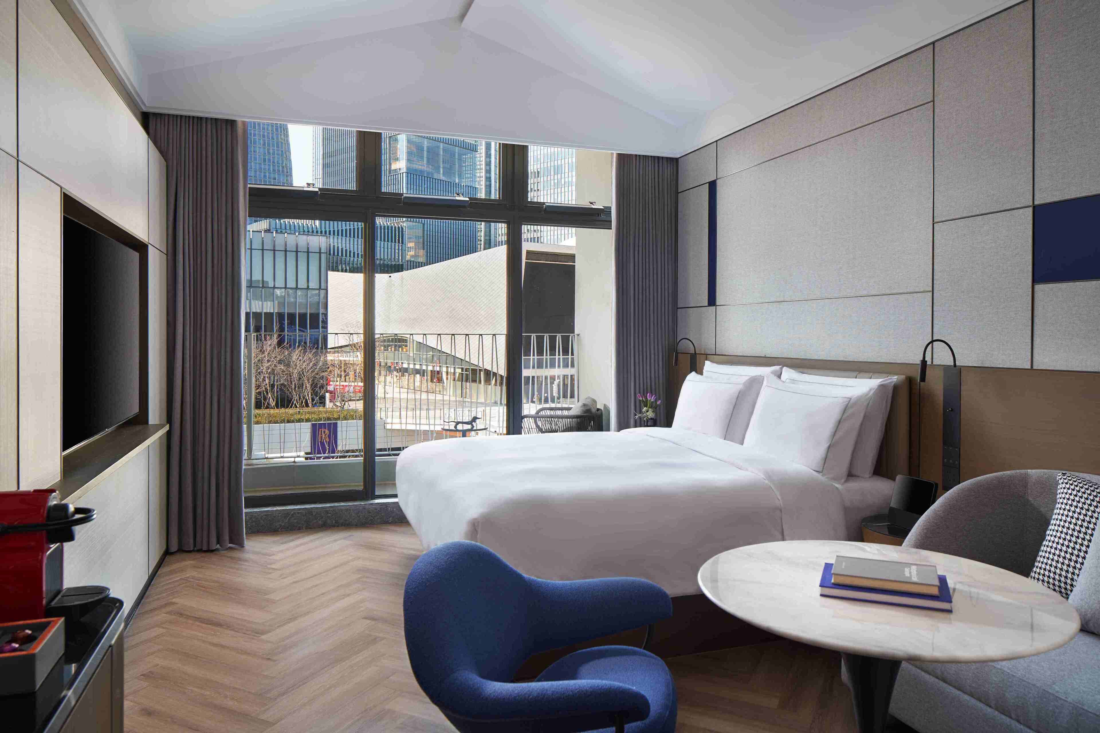 A hotel room with a large bed, a sofa, a small table, and a TV.