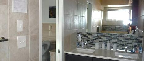 Ein Badezimmer mit gefliesten Wänden, einem Spiegel, einem Waschbecken und einem Schrank.