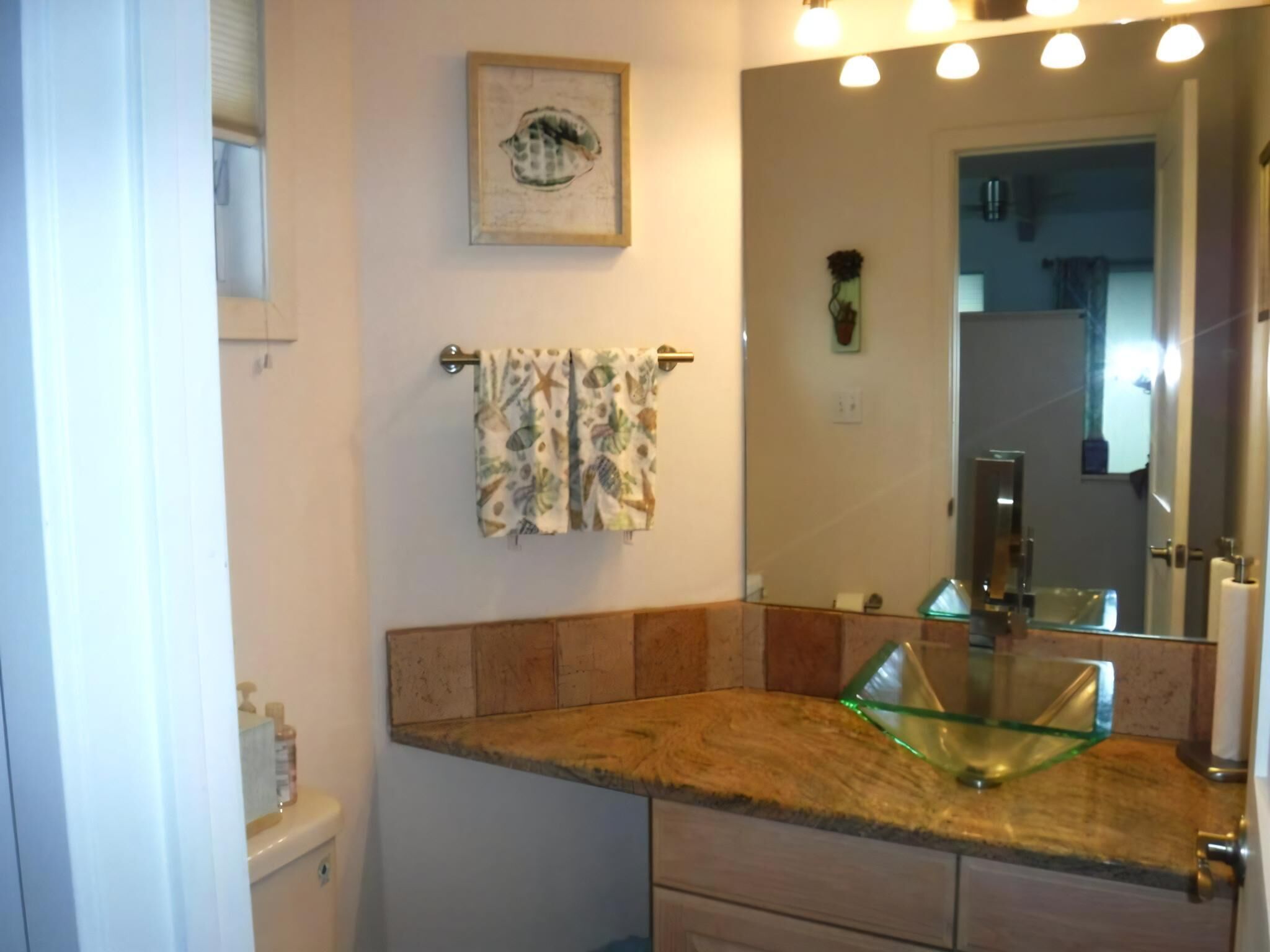 Une salle de bain avec un lavabo en verre, un meuble-lavabo en bois et un porte-serviettes orné de serviettes à motifs.
