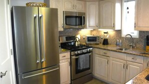 A kitchen with stainless steel appliances, granite countertops, and light wood cabinets.