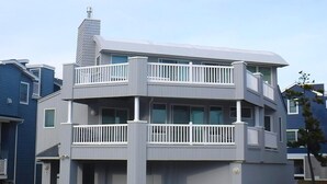 A multi-story residential building with balconies, a visible chimney, and a number '7' on the door.