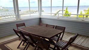 A covered outdoor seating area with a table and chairs, overlooking a waterfront. - 170F Sea Pine Dr, LLC 736 (Loveladies)