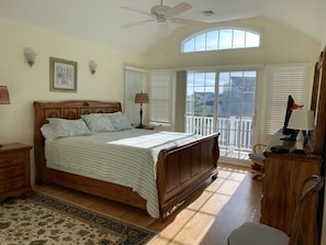 A bedroom with a large bed, a ceiling fan, a window with blinds, a desk with a lamp, and a view of the outside. - 4 bedroom accommodation in North Beach (North Beach)