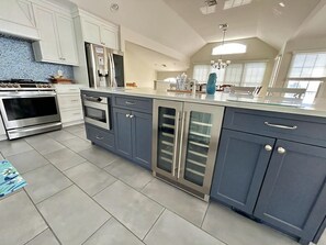 A modern kitchen with stainless steel appliances, a large island with a sink, and a window providing natural light.