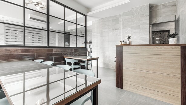 Una cocina moderna con una mesa de comedor de vidrio, baldosas claras y una pared de acento de madera.