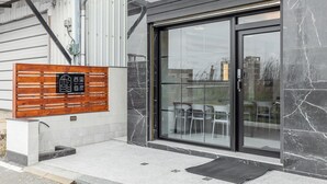 Una entrada moderna de edificio con un letrero de madera, puertas de cristal y fachada de baldosas.