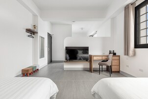 Una habitación de hotel moderna con una cama, un escritorio, una silla y un televisor.