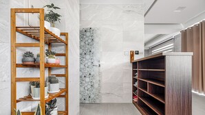 Un vestíbulo de hotel moderno con un estante de madera para plantas, una pared de mármol con diseños circulares y una unidad de almacenamiento de madera oscura.