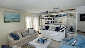 Ein modernes Wohnzimmer mit einer Couch, einem Couchtisch, einem Bücherregal und einem Bild an der Wand.