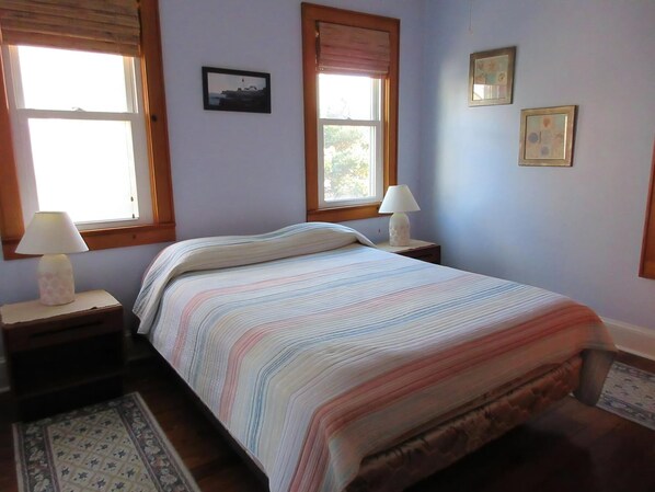 A bedroom with a bed, two nightstands, a window, and a door.