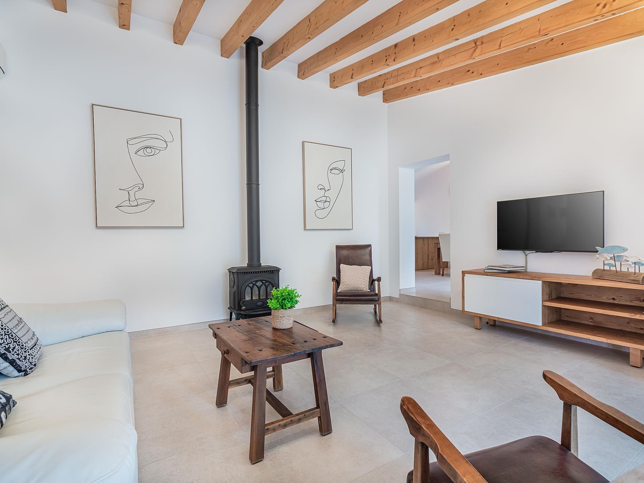 Ein modernes Wohnzimmer mit Holzboden, einem schwarzen Ofen, einem Fernseher und einem Sofa.