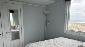 Une chambre à coucher avec un lit, une porte, une lampe et une fenêtre donnant sur un beau paysage.