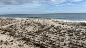 Une plage au paysage sablonneux, avec une clôture au premier plan.