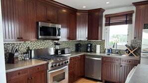 Une cuisine moderne avec des meubles en bois, une cuisinière en acier inoxydable, un four à micro-ondes et un lave-vaisselle.