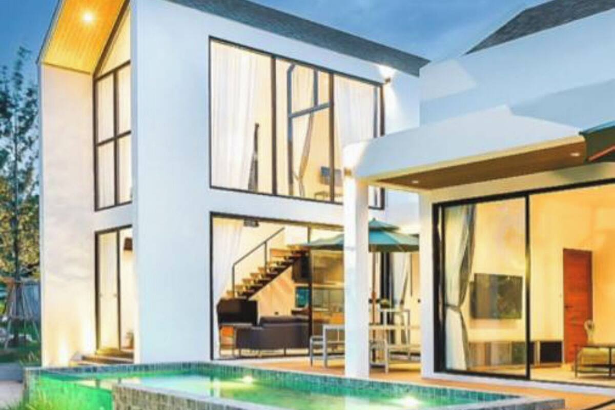 A modern two-story house with a swimming pool, outdoor seating, and a brick fire pit.