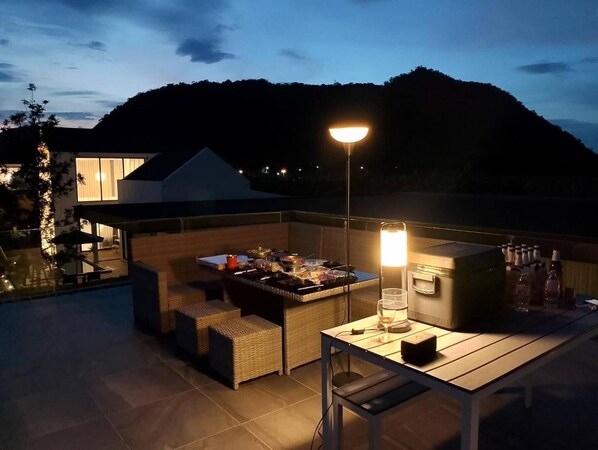 Un área de comedor al aire libre con una mesa, sillas y una parrilla.