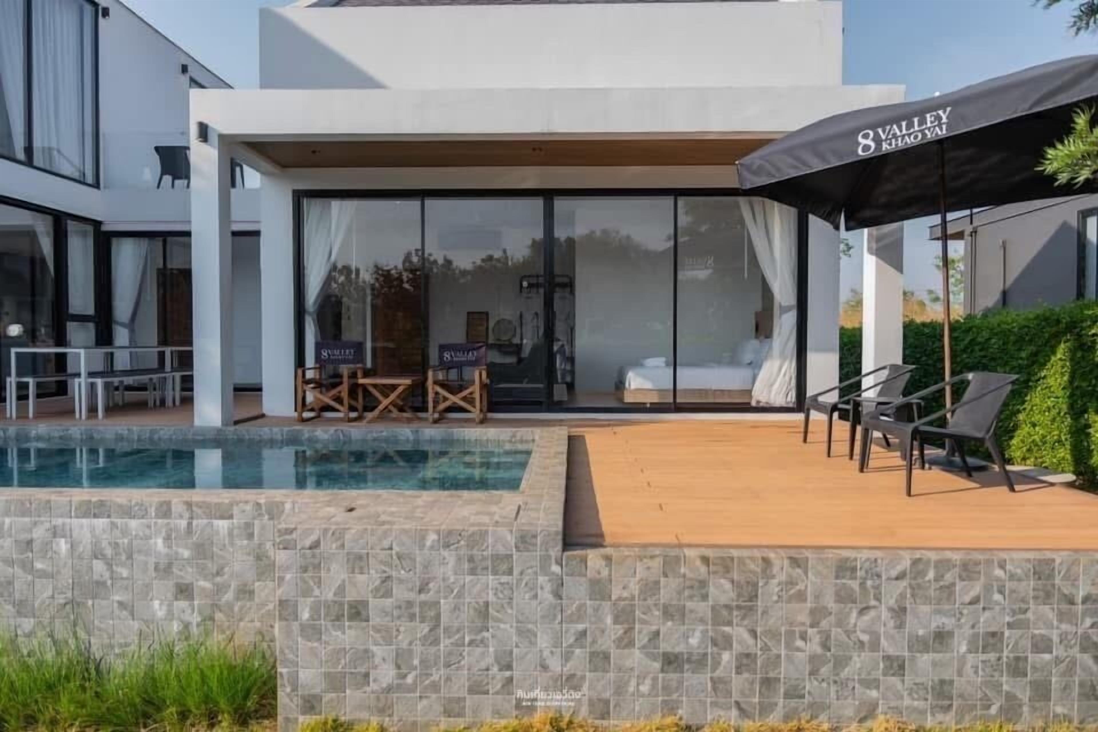 Hotel moderno com piscina, área de estar externa e um grande guarda-sol.