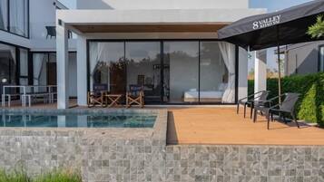 Hotel moderno com piscina, área de estar externa e um grande guarda-sol.