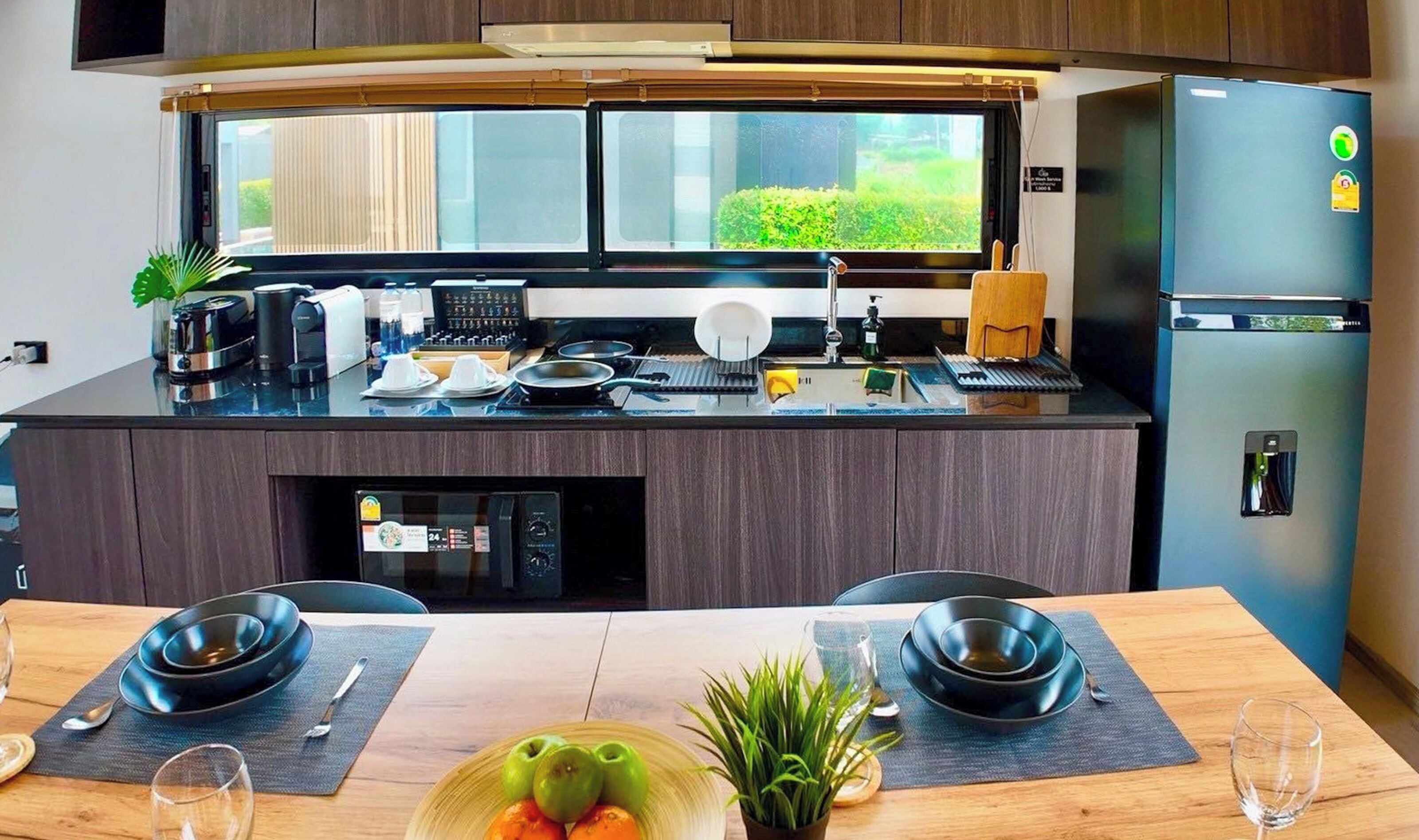 Una cocina moderna con horno empotrado, refrigerador y ventana con vista a un jardín.