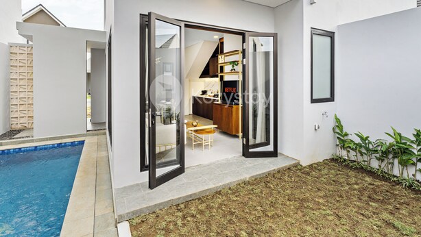 A modern house with an open patio, a swimming pool, and a kitchen visible through the open door. - Serila Villa by Kozystay - Jimbaran (Jimbaran)