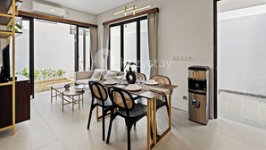 A modern dining area with a wooden table, black chairs, and a water dispenser. - Serila Villa by Kozystay - Jimbaran (Jimbaran)
