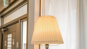 A hotel room with a wooden desk, a lamp, a charging station, and two potted plants. - HANASTAY NODA (Osaka)