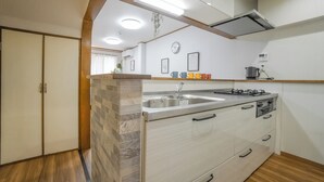 A modern kitchen with a built-in stove, sink, and storage cabinets. - HANASTAY NODA (Osaka)