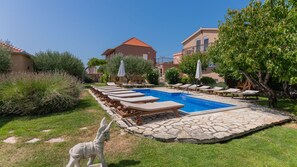 A pool area with lounge chairs, a stone pool, and a statue of a horse.