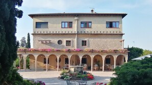 A two-story building with a courtyard, featuring a fountain, outdoor seating, and flower arrangements. - Villa Paradiso (Sirmione)