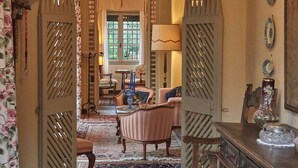 A spacious living area with a large chandelier, a fireplace, and a dining table with chairs. - Villa Paradiso (Sirmione)