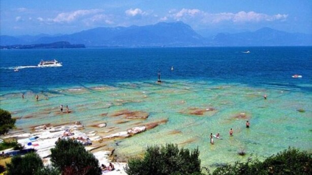A coastal area with clear waters, boats, and a distant mountain range. - Villa Paradiso (Sirmione)
