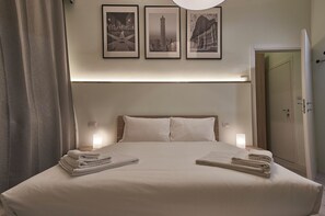 Camera d'albergo con un letto, due cuscini, un comodino, una lampada e tre quadri appesi al muro.