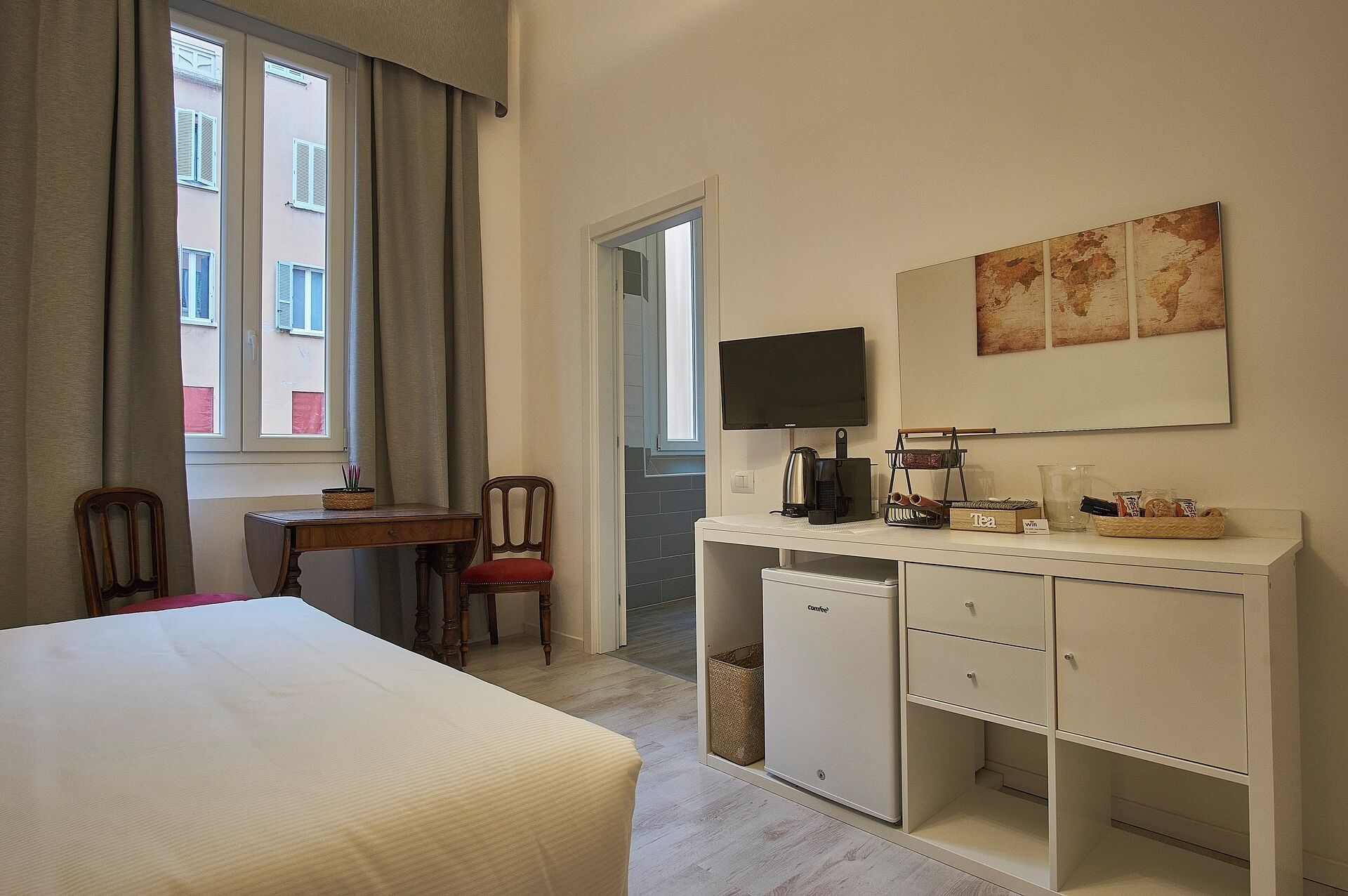 Ein Hotelzimmer mit einem Bett, einem Schreibtisch mit Computer, einer Kaffeemaschine und einem Fernseher.