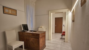 A room with a wooden desk, a chair, a framed certificate on the wall, and a door leading to another room. - Cuore di Bologna Suites (Bologna)