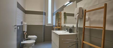 Un baño moderno con inodoro, lavamanos y zona de ducha.