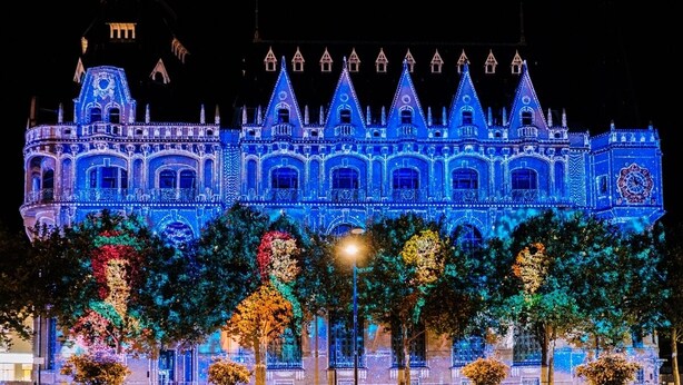 Un grand bâtiment illuminé, doté d’une façade rappelant celle d’un château, avec de nombreuses tours et des fenêtres en arc de cercle.