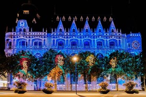 Un grand bâtiment illuminé, doté d’une façade rappelant celle d’un château, avec de nombreuses tours et des fenêtres en arc de cercle.