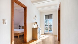 A hallway with wooden flooring, a bed, a dresser, and a window with a view. - Holiday Home 'Hof Vilmnitz 22 B' with Private Terrace, Private Garden and Wi-Fi (Putbus)