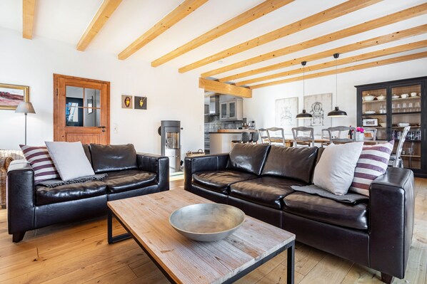 A living room with two leather sofas, a wooden coffee table, and a kitchen in the background.