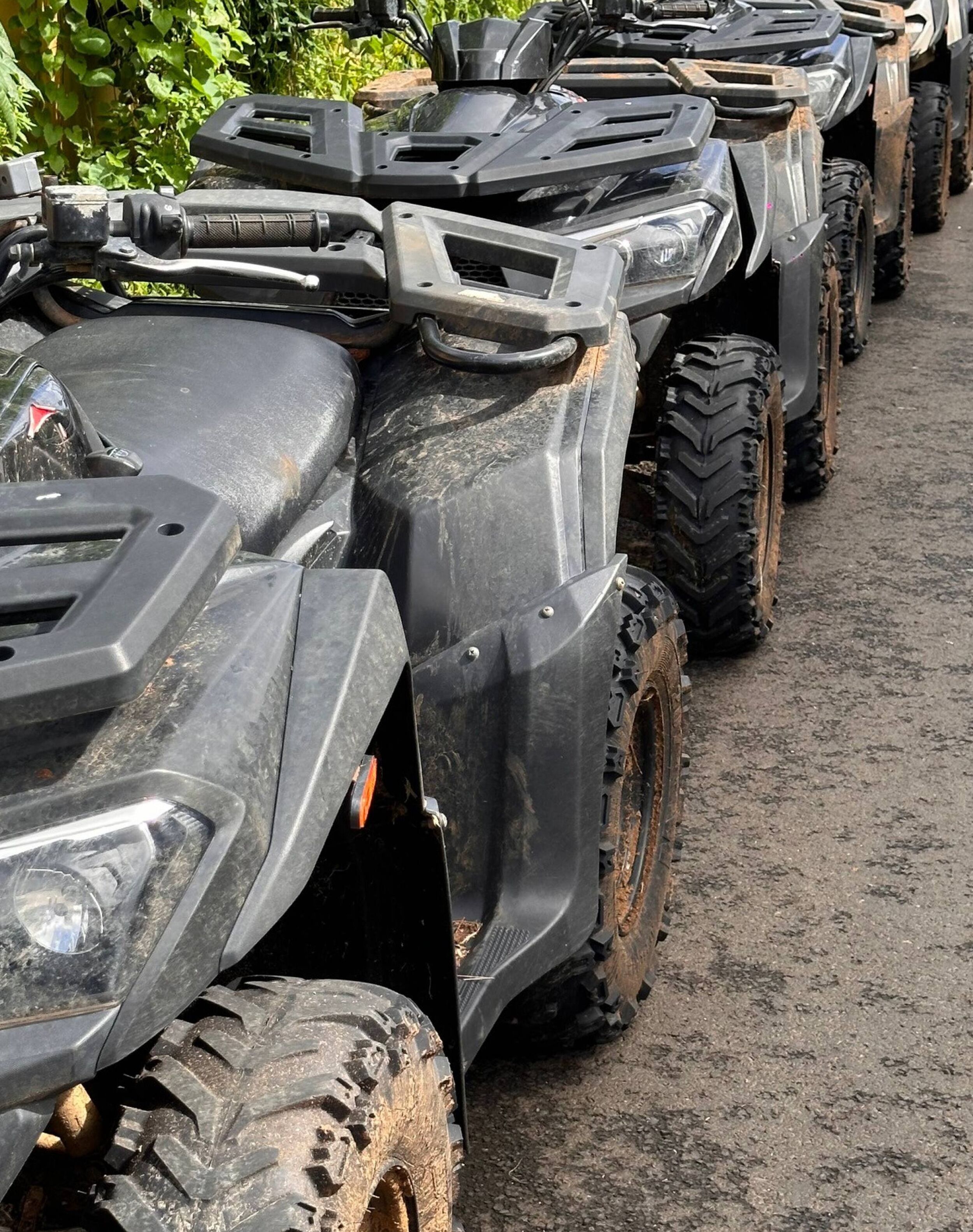 Een rij ATVs op een onverharde ondergrond.