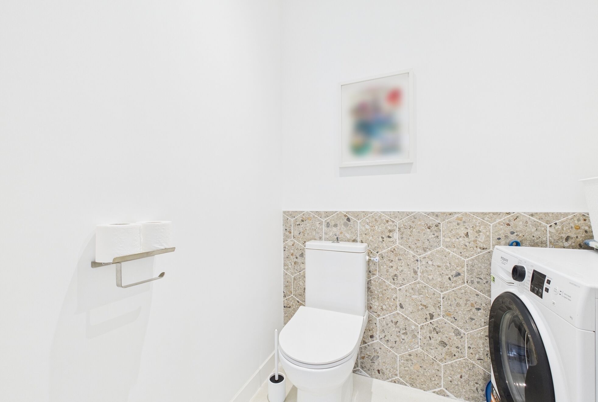 Une salle de bain moderne équipée de toilettes, d’un lave-linge et d’un porte-rouleau de papier toilette.