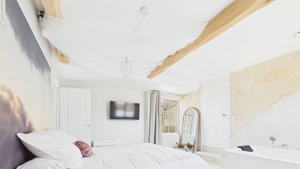 A bedroom with a bed, a bedside table, a mirror, a window, and a bathroom with a bathtub. - Comfortable cocoon 400m from Saumur cellars, close to golf course, IFCE, Loire... (Saumur)