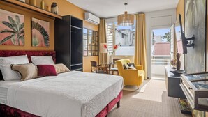 Habitación de hotel con una cama grande, un escritorio, una silla, un televisor y un balcón con vistas.