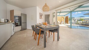 A modern kitchen with a dining area, a large window, and a view of a swimming pool. - 2 Villas with 2 Swimming Pools (Sainte-Luce)