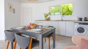 A compact kitchen with a dining area, a washing machine, and a window with a view of greenery. - 2 Villas with 2 Swimming Pools (Sainte-Luce)