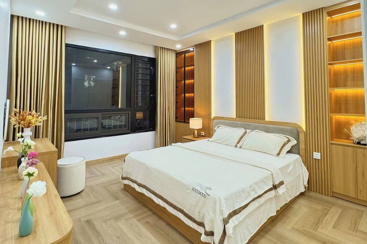 Un dormitorio moderno con una cama grande, paneles de madera, luces empotradas en el techo y vistas a la ciudad.