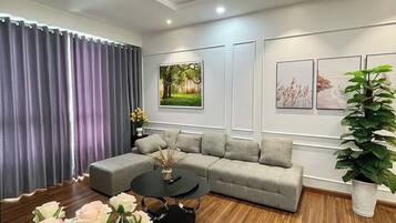 A modern living room with a grey sectional sofa, a round coffee table, and a large potted plant.